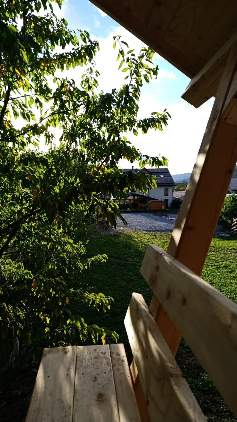 The guesthouse seen from the garden, through the branches, with mountains behind